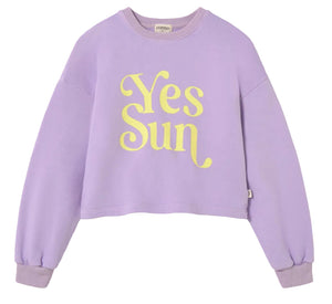 The Cozmo Girls' Vega Sweatshirt is a lavender fleece with a crew neck, long sleeves, and a bold "Yes Sun" motif in large yellow letters on the front.