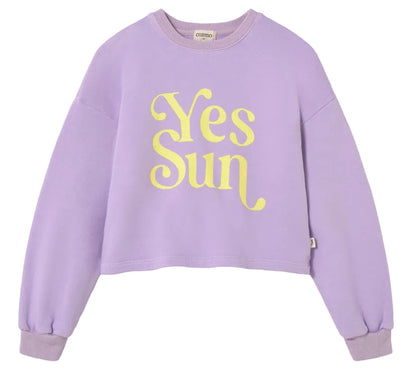 The Cozmo Girls' Vega Sweatshirt is a lavender fleece with a crew neck, long sleeves, and a bold "Yes Sun" motif in large yellow letters on the front.