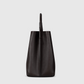 Side view of the Victoria Beckham Victoria Bucket bag, crafted from dark tan nappa leather with a single top handle and a modern look.
