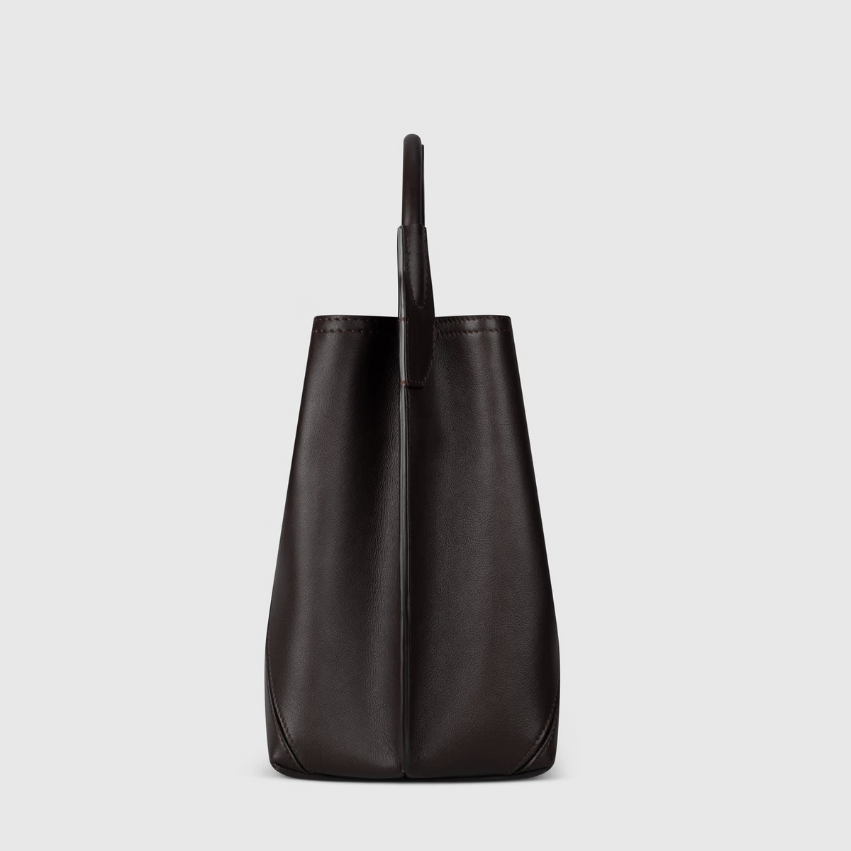 Side view of the Victoria Beckham Victoria Bucket bag, crafted from dark tan nappa leather with a single top handle and a modern look.