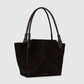 The Victoria Suede Tote by Victoria Beckham features black suede and two long black leather handles, shown on a light gray background.