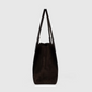 The Victoria Suede Tote by Victoria Beckham is a dark brown suede shoulder bag with two handles and a minimalist side profile against a plain light background.