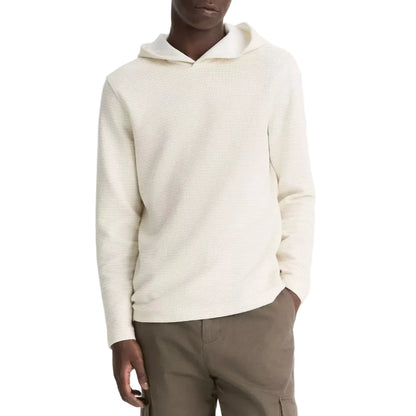 A person wearing the vince Variegated Stripe Double Face Hoodie in light beige with a jersey-lined hood and olive green pants stands with one hand in their pocket against a white background.