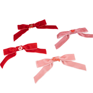 The Meri Meri Velvet Bows with Charms Hair Clips set includes four romantic red and pink bows, each with decorative clips featuring various shapes and symbols, making it a perfect Valentine's gift.