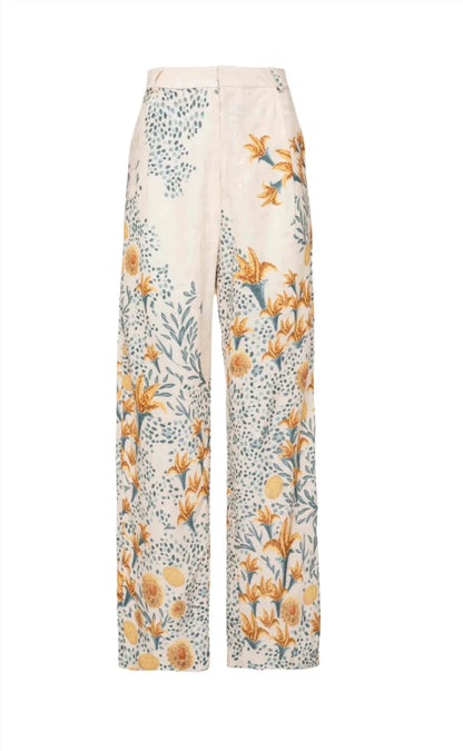 Agua By Aguabendita's Agua By Aguabendita Florecer Pant is a pair of white wide-leg trousers with a high waist, adorned with a vibrant floral and leaf print in shades of blue, yellow, and green. Crafted from 100% viscose for a luxurious feel.