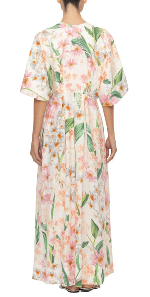 Rear view of a person wearing the Agua by Aguabendita Gesto Maxi Kaftan, a floral-patterned, ankle-length dress. This piece from Agua By Aguabendita features short sleeves and a loose fit with a cinched waist, making it one of the most coveted dresses crafted from breathable linen.