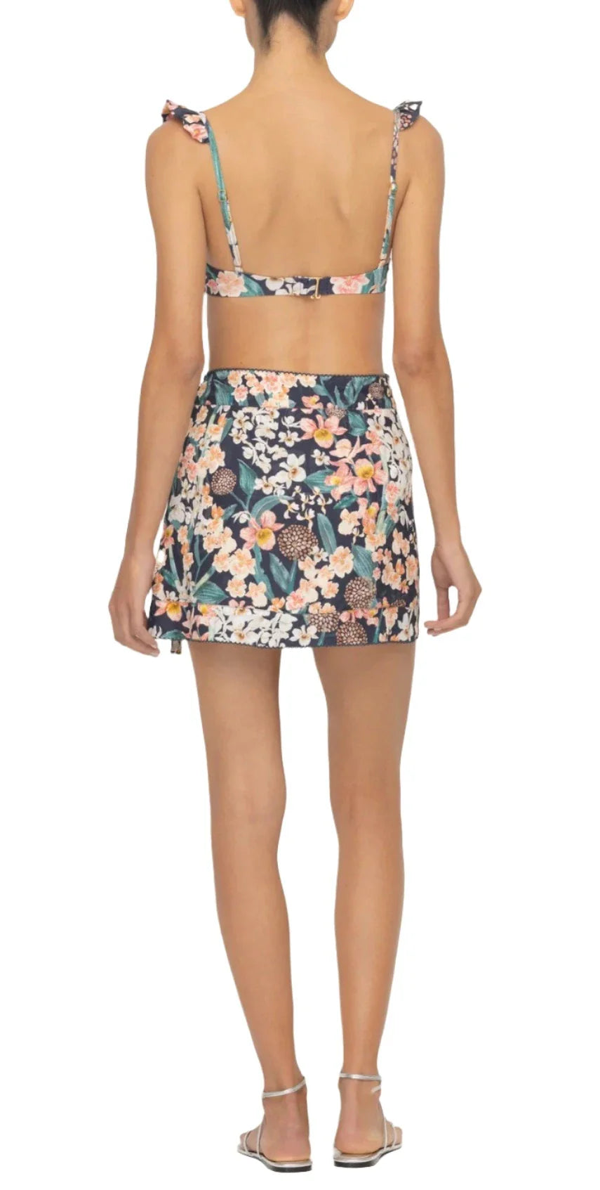 Back view of a person wearing a floral bikini with a high-waisted skirt and sandals, featuring the chic Luna Mini Pareo from Agua By Aguabendita.