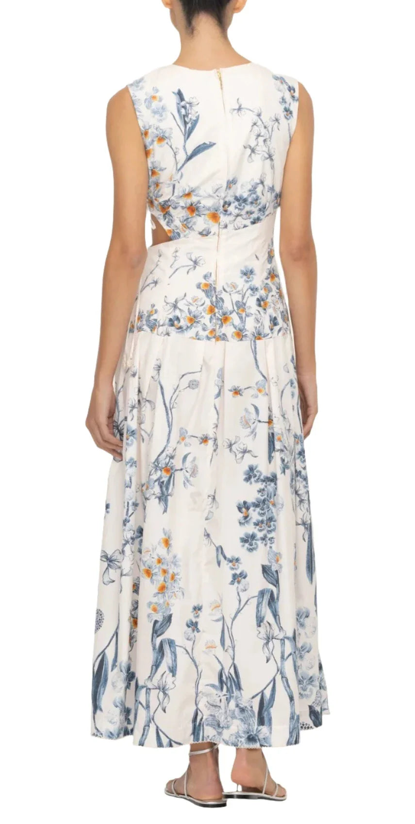 A person is wearing an Agua By Aguabendita Otono Petalo sleeveless white midi dress with blue and orange floral patterns. The cotton poplin dress, featuring a cutout at the waist, showcases the person standing with their back facing the camera.