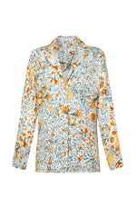 The Agua By Aguabendita Silice Shirt is a versatile long-sleeved shirt adorned with a colorful floral pattern featuring yellow, orange, and green flowers on a white background.