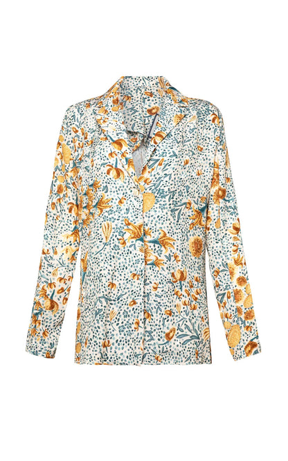 The Agua By Aguabendita Silice Shirt is a versatile long-sleeved shirt adorned with a colorful floral pattern featuring yellow, orange, and green flowers on a white background.