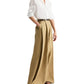 Someone wears the TWP Tied Down Shirt, a white band collar button-down, tucked into high-waisted wide-leg tan trousers with a belt and brown sandals.