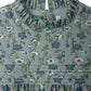 Close-up of Bonpoint's Girls' Topaz Dress, featuring an embroidered collar, button back closure, and pleated Liberty velvet fabric in blue and green.