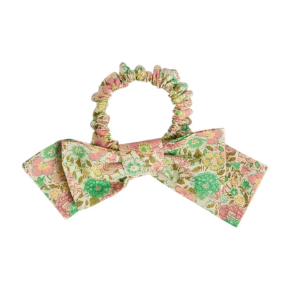 The Bonpoint Jeani Scrunchie in Pink Liberty Fabric features a floral design and a large matching bow in soft pastel shades.