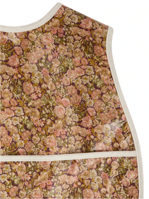 Close-up of the Bonpoint Jlip Adjustable Bib, crafted with Liberty Fabrics, showcasing a brown, pink, and cream floral pattern with white trim on the edges and front pocket.