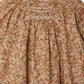 A close-up of the Bonpoint Baby Girls' Jia Smocked Jumpsuit in Liberty fabric, featuring gathered pleats and hand-embroidered smocking near the neckline.