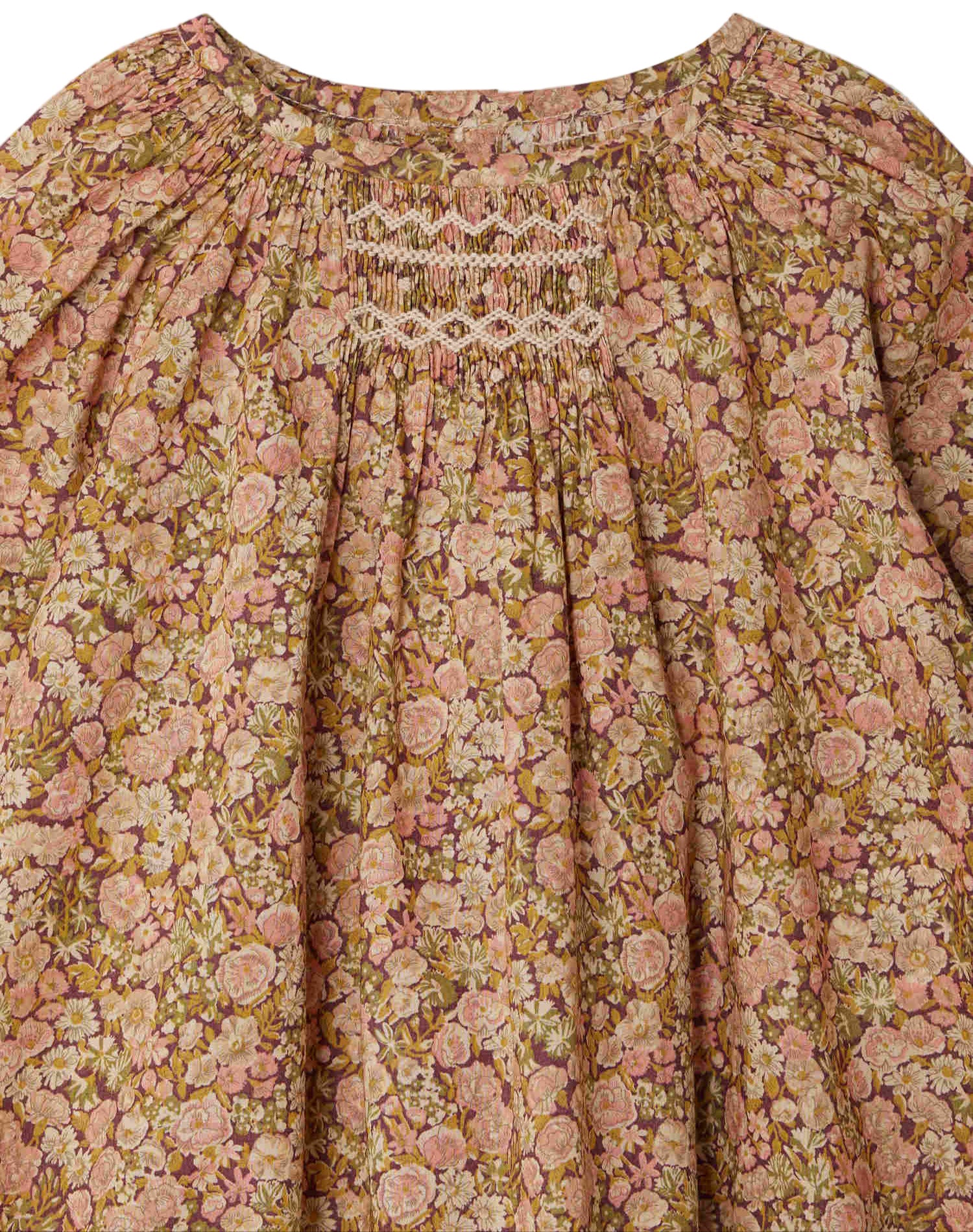 A close-up of the Bonpoint Baby Girls' Jia Smocked Jumpsuit in Liberty fabric, featuring gathered pleats and hand-embroidered smocking near the neckline.
