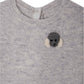 The Bonpoint Baby Boys' Tinoe All in One Outfit is a light gray knit with snap buttons and a small crocheted gray and white dog patch on the upper left chest.