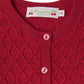 Close-up of the Bonpoint Baby Girls' Jarancia cardigan, featuring a fancy wool stitch diamond pattern, two pink buttons, and a Bonpoint label marked 6M at the neckline.