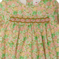 A close-up of Bonpoint’s Baby Girls’ and Girls’ Félicie Smocked Dress, crafted from Liberty fabric with pink, green, and beige floral smocking across the chest.