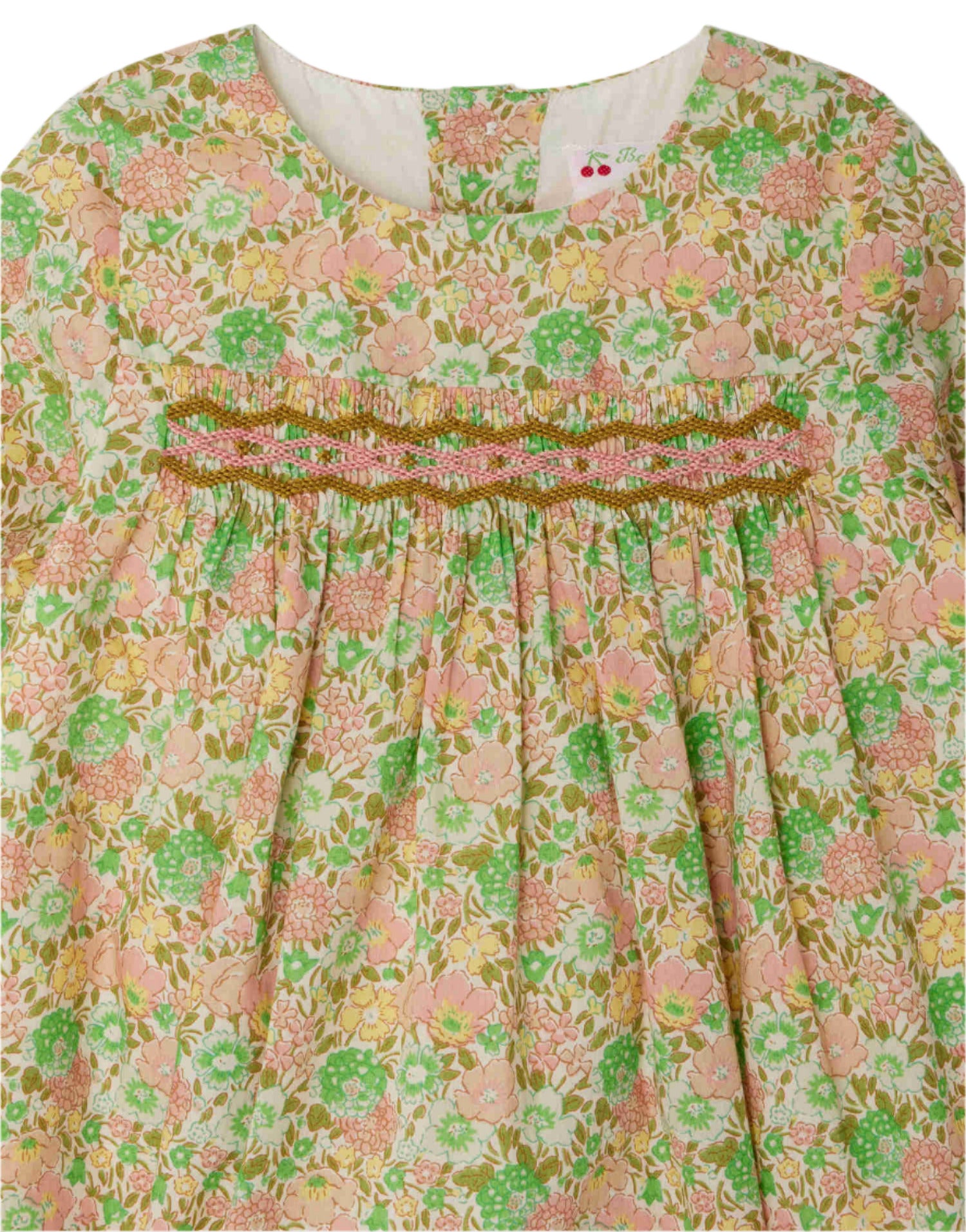 A close-up of Bonpoint’s Baby Girls’ and Girls’ Félicie Smocked Dress, crafted from Liberty fabric with pink, green, and beige floral smocking across the chest.