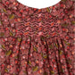 Close-up of the Bonpoint Juju Smocked Dress for babies and girls, crafted in organic cotton Liberty fabric with a maroon floral print, featuring smocking and gathered pleats below the yoke.