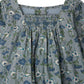 Close-up of Bonpoint’s Baby Girls' and Girls' Jada Smocked and Embroidered Dress, featuring blue and white florals, a square neckline, smocked chest, gathered fabric, and crafted from soft Liberty velvet.