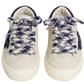 A pair of Bonpoint x Golden Goose Baby Sneakers in white, featuring thick blue and white patterned laces, are displayed side by side on a plain white background, viewed from above.