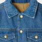 Close-up of Bonpoint’s Boys’ Marvin Reversible Jacket with Embroidery on the Back. This organic cotton denim jacket features metal snap buttons, a visible collar, chest pockets, and a tan quilted lining inside—combining classic style with comfort and durability.