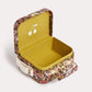 Introducing the Girls’ Aimane Travel Bag by Bonpoint—a small box crafted from Liberty fabric featuring a floral pattern, designed with an open lid, a yellow interior adorned with a white cherry motif, and finished with a beige strap attached to the side.