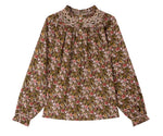 The Girls’ Petale Blouse by Bonpoint is a long-sleeve top made from Liberty fabric, showcasing a multicolored floral print, ruffled cuffs, a lace collar, and front buttons, displayed on a white background.