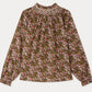 The Girls’ Petale Blouse by Bonpoint is a long-sleeve top featuring a floral pattern in pink, green, and brown hues, crafted from soft organic cotton. It is detailed with hand-embroidered smocking on the high neckline and gathered cuffs for an elegant touch.
