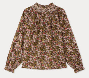 The Girls’ Petale Blouse by Bonpoint is a long-sleeve top featuring a floral pattern in pink, green, and brown hues, crafted from soft organic cotton. It is detailed with hand-embroidered smocking on the high neckline and gathered cuffs for an elegant touch.