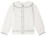 Bonpoint Girls’ Maneke Blouse with Peter Pan Collar Embroidery, a white long-sleeve blouse adorned with a ruffled vintage Peter Pan collar and wavy black trim accenting the collar, button placket, cuffs, and hem.