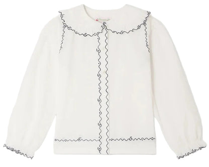 Bonpoint Girls’ Maneke Blouse with Peter Pan Collar Embroidery, a white long-sleeve blouse adorned with a ruffled vintage Peter Pan collar and wavy black trim accenting the collar, button placket, cuffs, and hem.