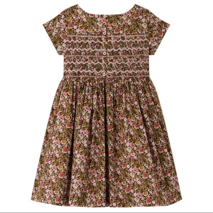 The Girls’ Duchesse Dress by Bonpoint features short sleeves and a floral print in pink, green, and brown hues. Made from soft organic cotton Liberty fabric, it is designed with a smocked bodice, three front buttons, and a gathered skirt.
