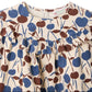 Close-up of the Girls’ Bevika Dress in Organic Cotton Velvet by Bonpoint, featuring a cream-colored fabric with a ruffled collar and a blue and brown abstract floral pattern.