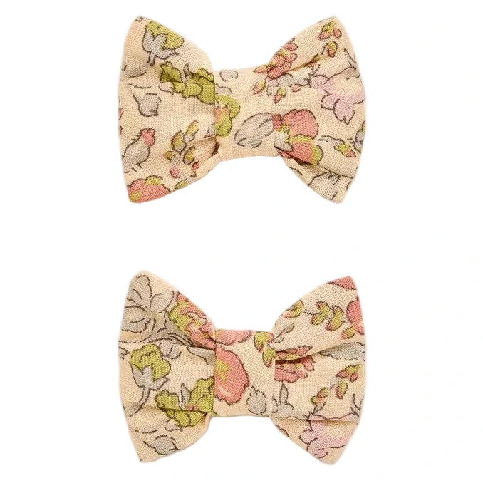 Two Miniclic Barette fabric hair bows by Bonpoint, crafted from Liberty Tana Lawn in a delicate floral pattern featuring pink, green, and beige tones, are displayed against a white background with one positioned above the other. These charming girls’ accessories are perfect for adding a touch of elegance to any outfit.