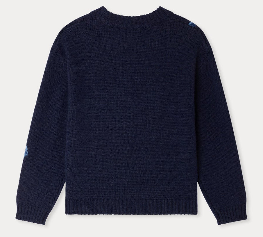 A navy blue, long-sleeve Girls’ Maxine Sweater by Bonpoint is displayed laid flat and viewed from the back, featuring ribbed cuffs, hem, and collar. Subtle blue patches accent one shoulder and sleeve, lending a playful detail to this charming sweater.