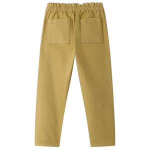 The Girls’ July Pants by Bonpoint are beige straight-leg pants for girls, made from organic cotton with an elastic waistband and two back patch pockets, pictured from the rear.