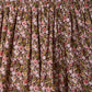 A curtain with a gathered top, adorned with a dense, vintage-inspired floral print in pink, red, green, and brown—echoing the classic pattern found on Bonpoint’s Girls’ Suzon Skirt.
