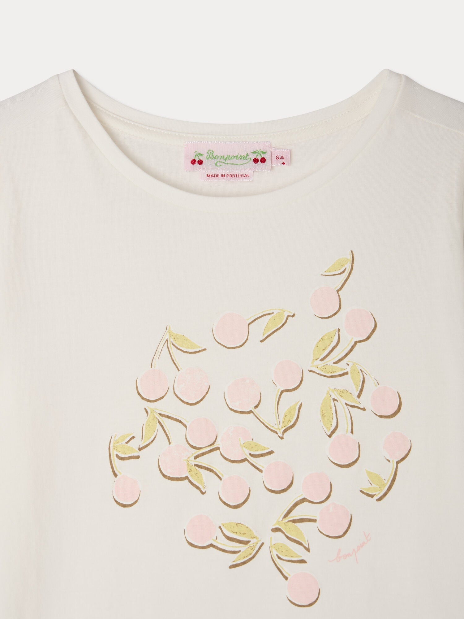 Close-up of the Girls’ Capricia T-Shirt by Bonpoint, crafted from organic cotton and featuring a pink cherry print with a green leaf design on the chest; the collar label displays “Bonpoint.”.