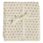Delicately wrapped in a cream ribbon bow, the Doudou Swaddle Blanket by Bonpoint features folded cream-colored organic cotton adorned with petite pink and green florals. This charming bundle is the perfect baby gift—soft against delicate skin and bringing a hint of vintage elegance to every nursery.