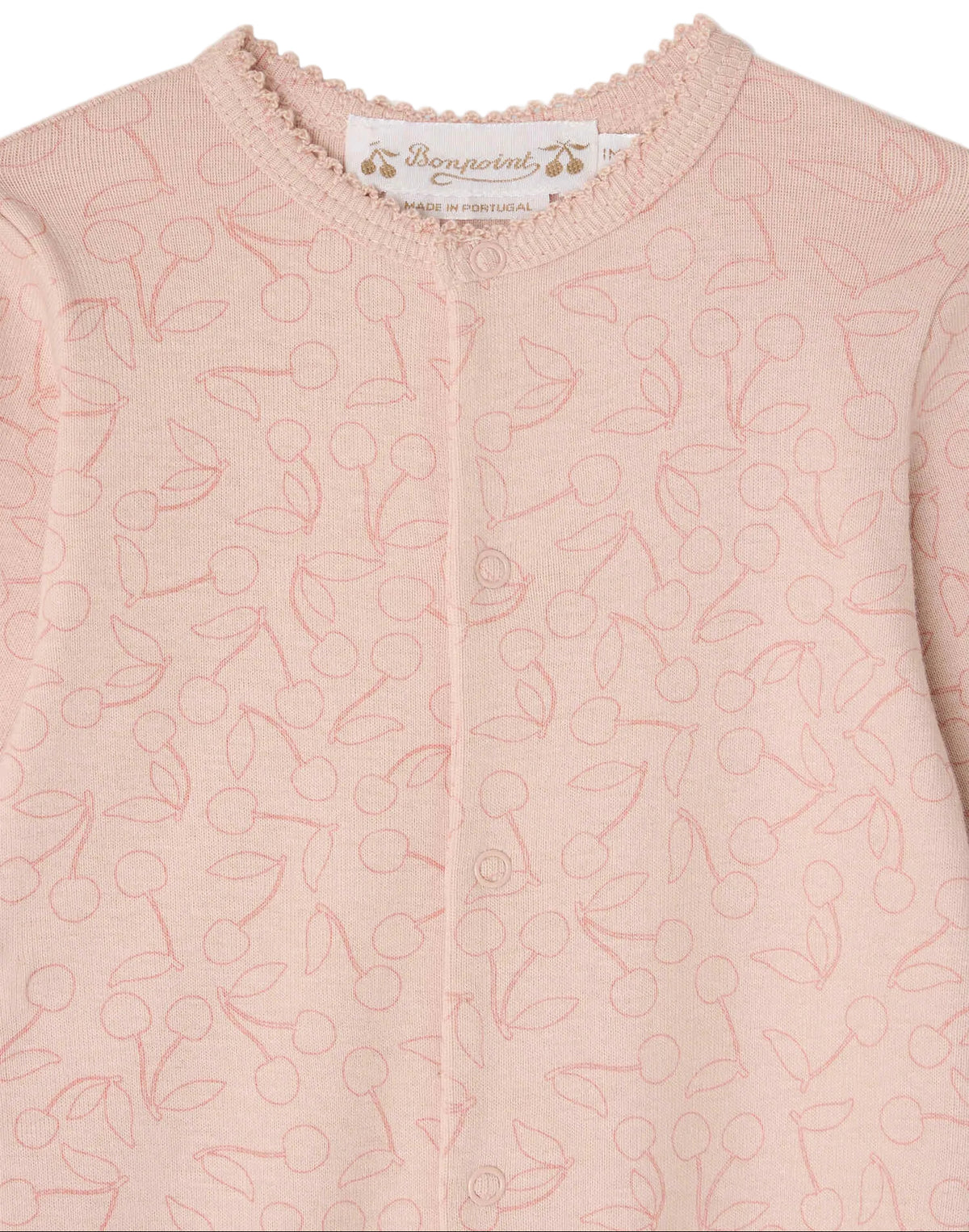 A close-up of a pale pink knit baby cardigan with a delicate cherry pattern, round neckline, and small front buttons. The brand label “Bonpoint” is visible inside the collar, making it a charming layering piece to pair with Baby Girls’ Golco Pajamas with Cherry Pattern for extra warmth.