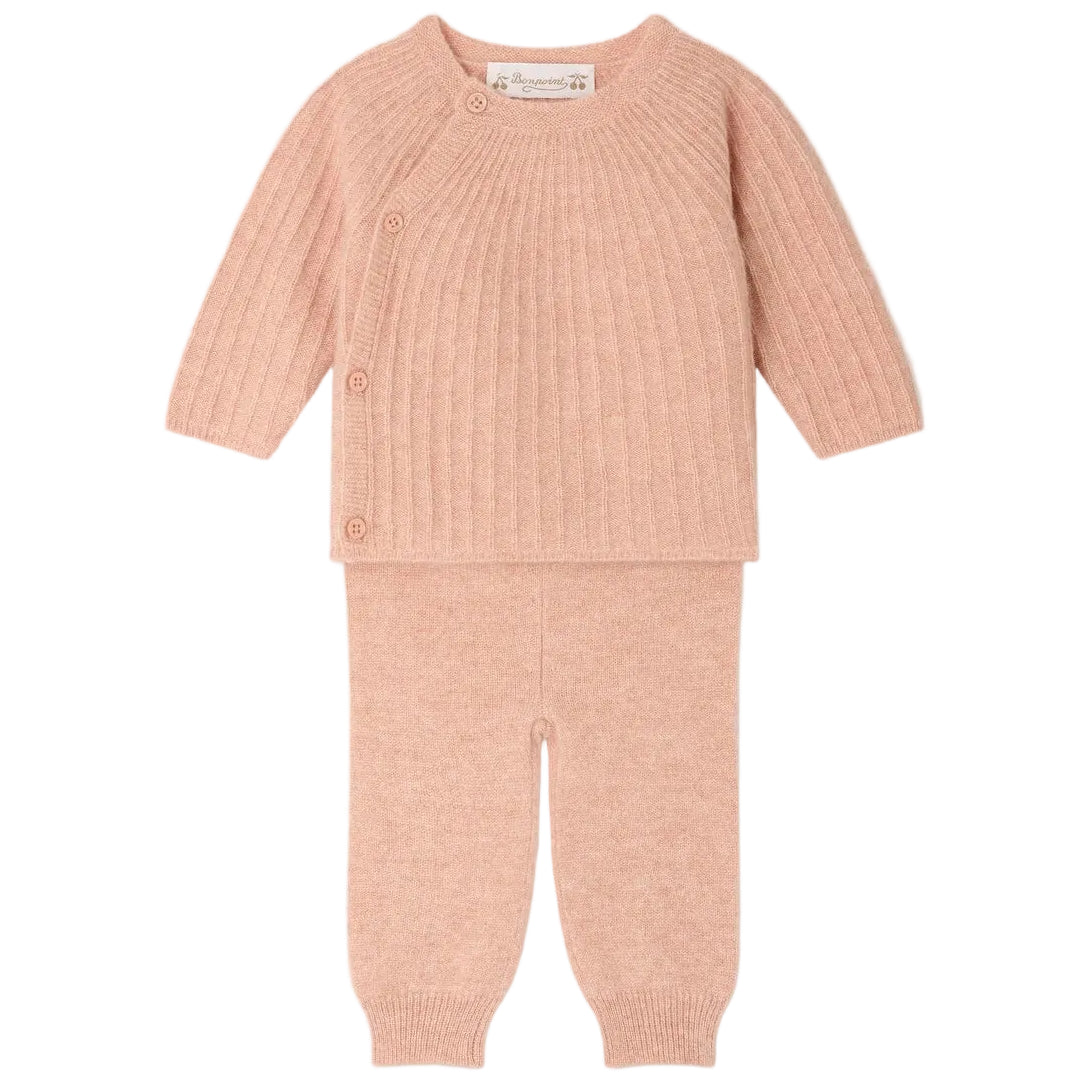 The Baby Girls’ Ging Fancy-Stitch Set in Cashmere by Bonpoint features a pink ribbed knit wrap-style top with side buttons and matching pants, both beautifully displayed flat on a white background. This decorative cashmere set brings unparalleled softness and charm to any little one’s wardrobe.