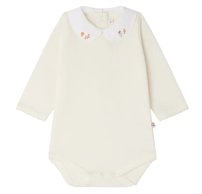 Bonpoint’s Baby Cygne LS Bodysuit is a long-sleeved, cream-colored piece crafted from soft organic cotton. It features a white Peter Pan collar delicately hand-embroidered with small florals and has convenient snap closures at the bottom.