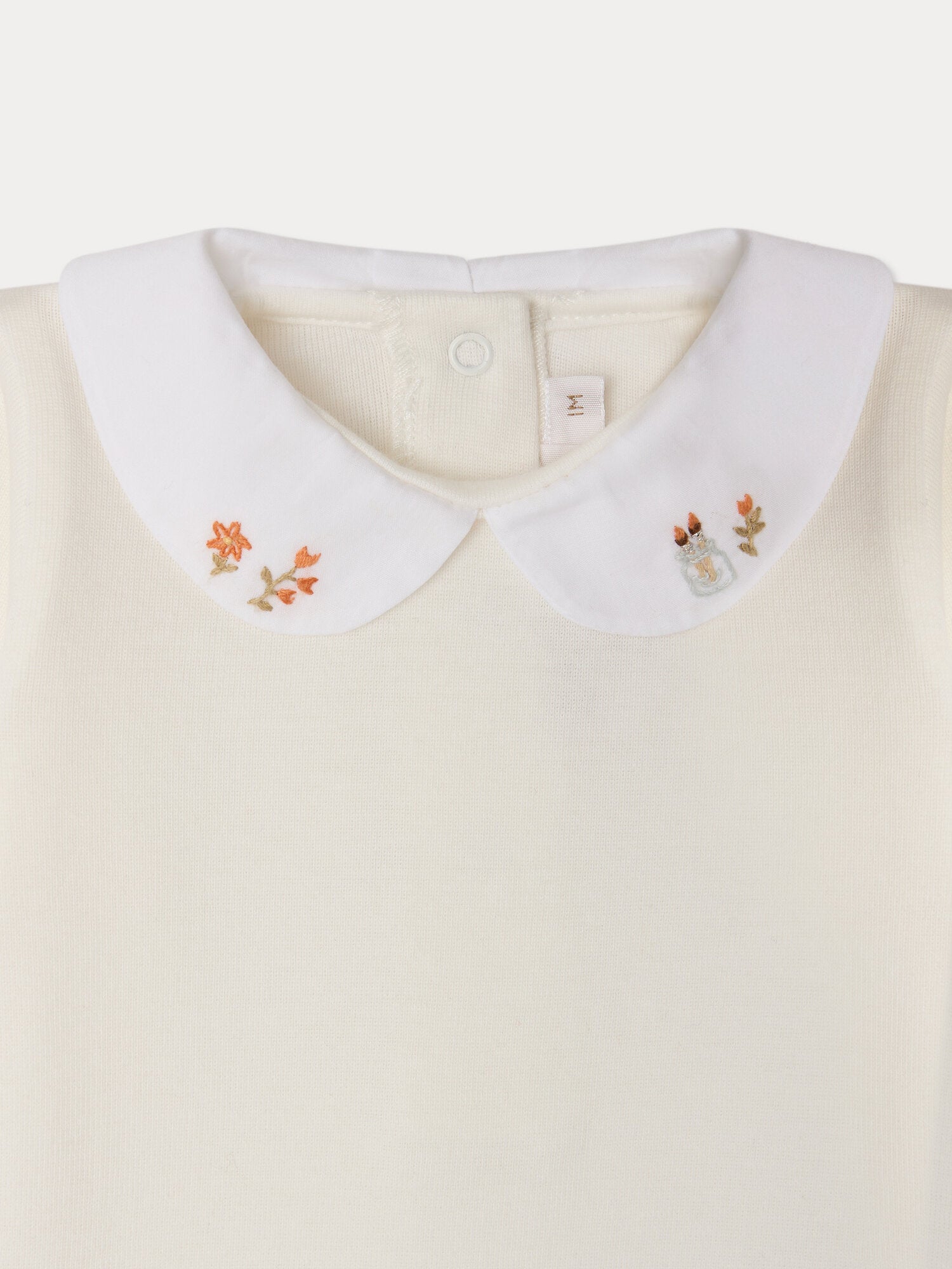 Close-up of the Bonpoint Baby Cygne LS Bodysuit in white, featuring a Peter Pan collar delicately hand-embroidered with small flowers and leaves on each tip. Crafted from soft organic cotton, this charming bodysuit is gentle on your baby’s skin.