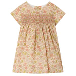 Bonpoint’s Baby Girls’ and Girls’ Maruska Dress features short sleeves, smocked and hand-embroidered detailing across the chest, a floral Liberty Tana Lawn fabric, and an A-line silhouette, shown against a plain background.