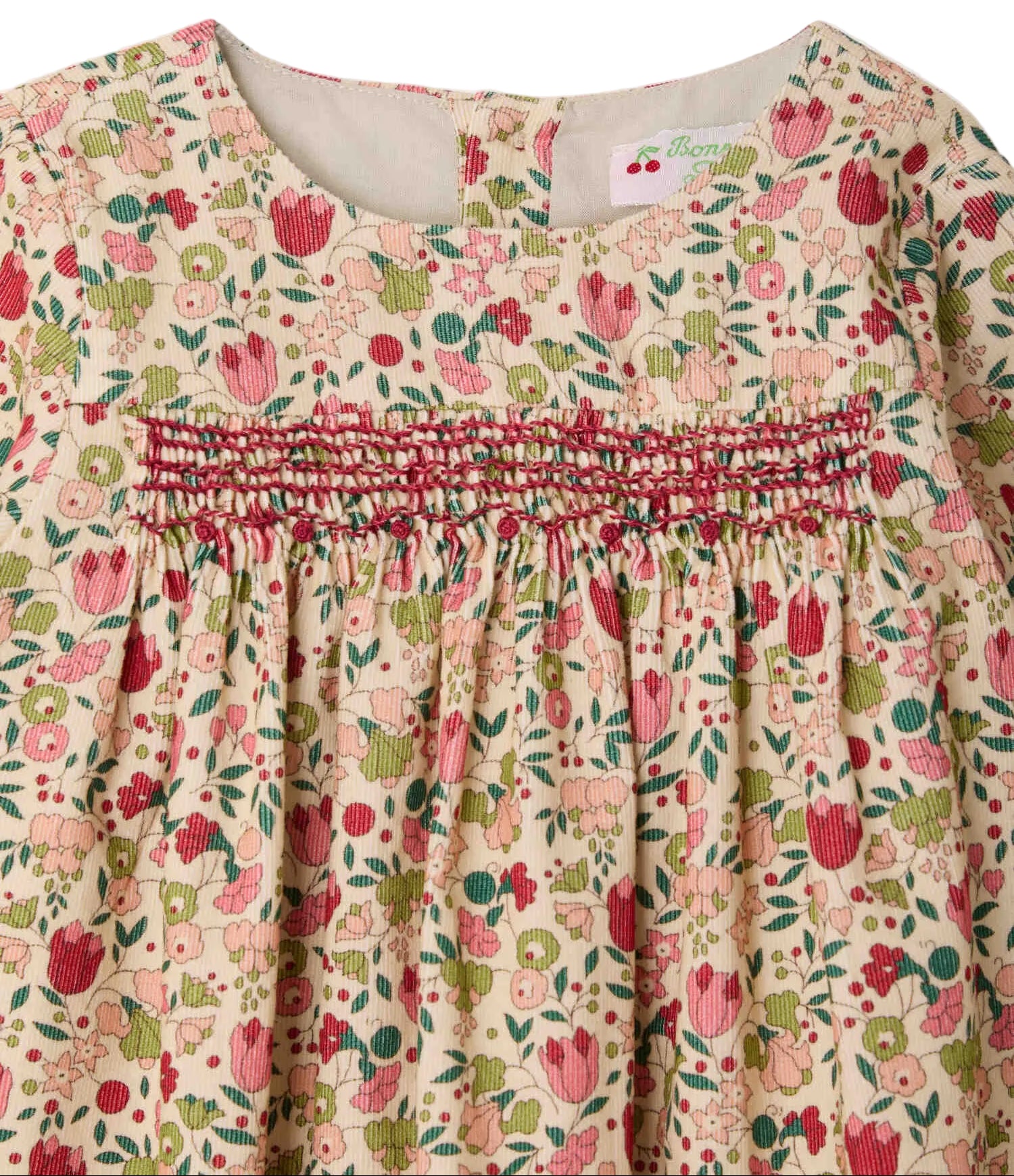 A close-up of the Bonpoint Baby Girls’ and Girls’ Félicie Dress with Smocking and Hand Embroidery, showcasing its delicate floral motif in pink, red, and green hues, hand-embroidered smocked detailing across the chest, and a classic round neckline.