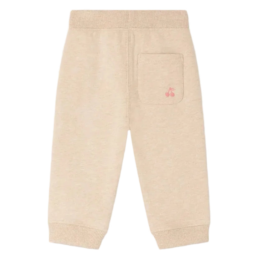The Bonpoint Baby Girls’ and Girls’ Bambo Beige Jogging Bottoms are crafted from soft organic cotton fleece, featuring a single back pocket adorned with a pink embroidered cherry, shown against a white background.