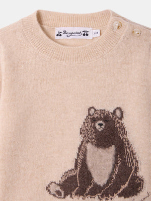 The Bonpoint Baby and Kids’ Almire Pullover is a beige knit sweater with two shoulder buttons, featuring a charming graphic of a seated brown bear on the front.